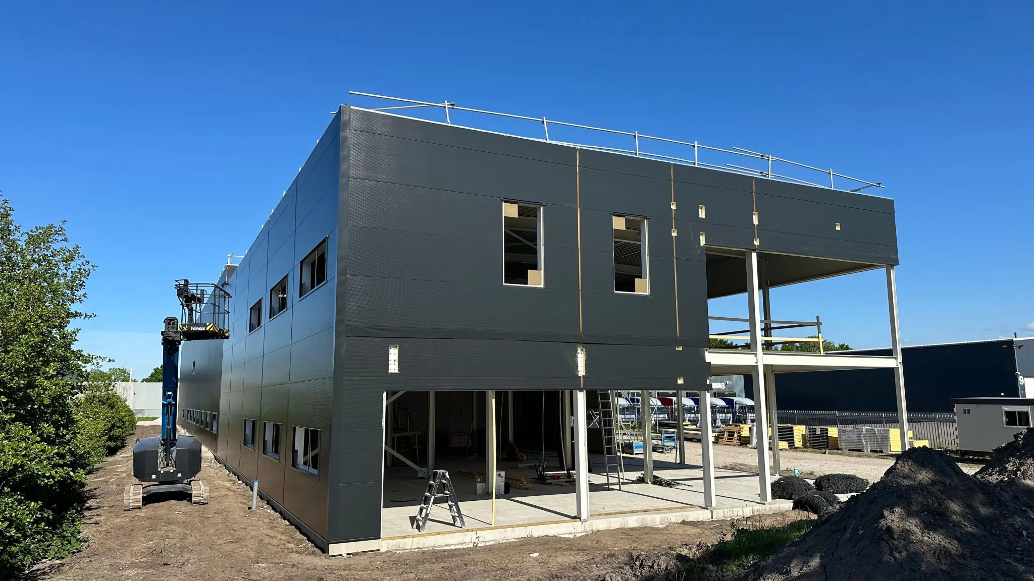 Op de foto is de voorkant van de bouw van het nieuwe pand te zien. Interieur door Into Sytle