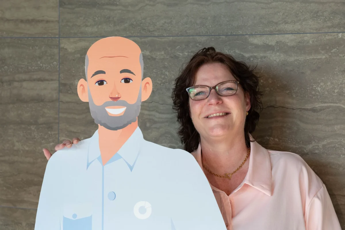 Myrna op de foto met ATO, onze mascotte en cartoon figuur.