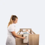 Zorgmedewerker bedient het EkaMove-paneel aan het voetenbord van een zorgbed en draait de cliënt naar zijligging
